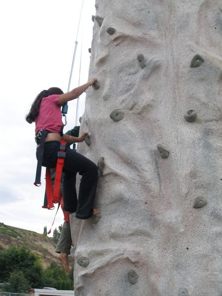 A couple girls racing to the top of the rock wall
