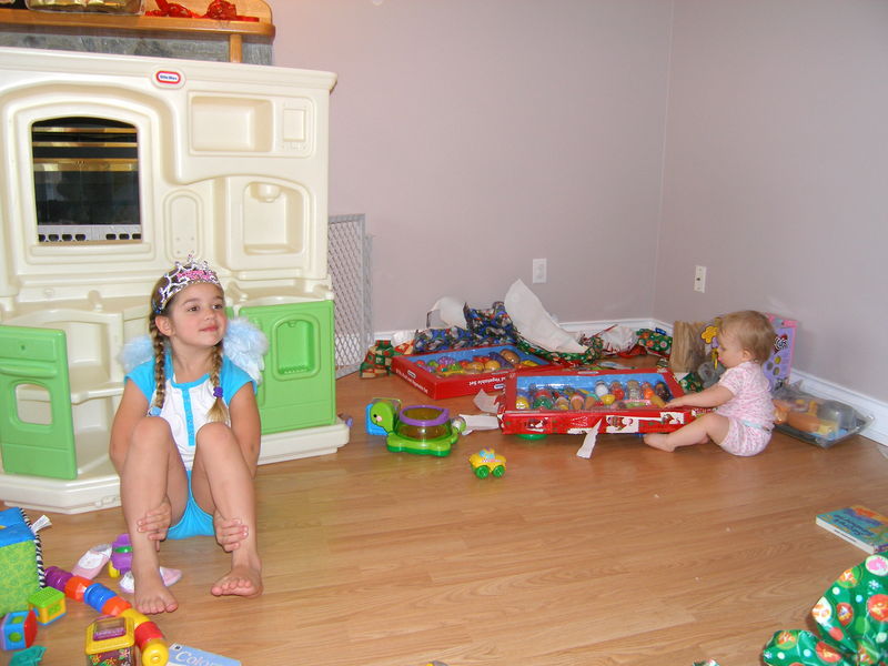 Kaija posing pretty in front of her new play kitchen while Maddi rumages Kaija's new wares

